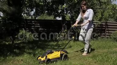 女孩正赤脚用黄色的割草机修剪一块凹凸不平的草坪